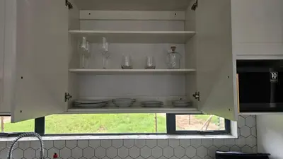 a kitchen with glasses and plates and a window at Modern Farmhouse, Pool, AC, Wi-Fi in Estate in Hazyview