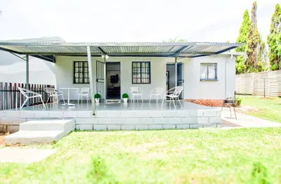 a small white house with a patio and chairs at Peaceful luxurious fully-equipped home in Centurion