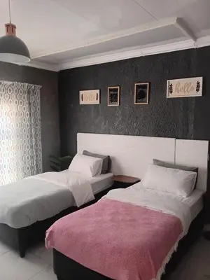 a bedroom with two beds and a wall with pictures at Comfort place 6 in Pretoria
