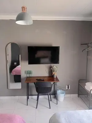 a room with a desk and a tv on a wall at Comfort place 6 in Pretoria