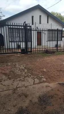 a black fence in front of a white building at Comfort place 6 in Pretoria