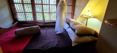 a bedroom with a couch and a dress hanging from a window at Mountain Haven Kaapsehoop in Kaapsehoop