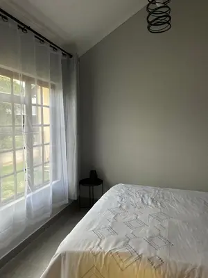 a white bedroom with a bed and a window at Pendleberry Grove 33 in Bela-Bela
