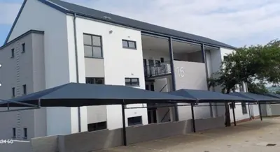 a building with blue umbrellas in front of it at Safubi 2 bedroom apartment in Nelspruit