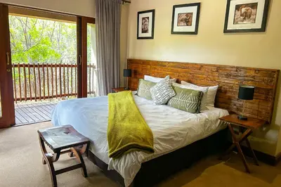 a bedroom with a large bed with a wooden headboard at Elements Bush Villa 18 in Warmbaths