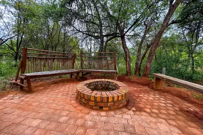 two benches and a fire pit on a brick patio at Elements Bush Villa 18 in Warmbaths