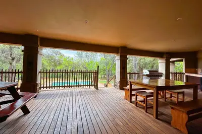 a large wooden deck with a table and benches at Elements Bush Villa 18 in Warmbaths