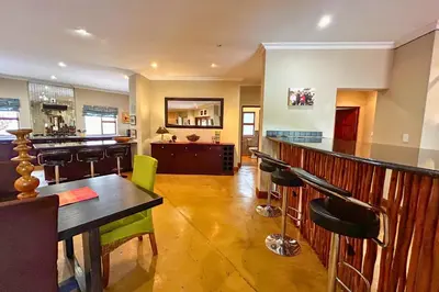 a bar with green chairs in a room at Elements Bush Villa 18 in Warmbaths