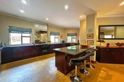 a large kitchen with a large island with bar stools at Elements Bush Villa 18 in Warmbaths