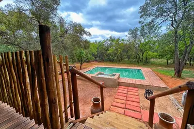 a swimming pool in a yard with a wooden fence at Elements Bush Villa 18 in Warmbaths
