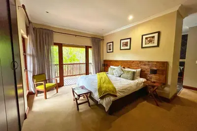 a bedroom with a large bed and a balcony at Elements Bush Villa 18 in Warmbaths
