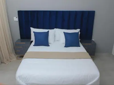 a bedroom with a large bed with blue headboard and pillows at MRF Lodge in Louis Trichardt