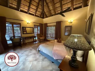 a bedroom with a bed and a table and a lamp at Zebula - Bushveld Waters - 20 Pax in Warmbaths