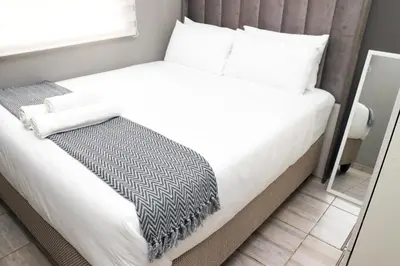 a bedroom with a bed with white sheets and a mirror at Grace View Guest House in Chartwell