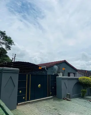 a house with a blue gate and a building at Mbombela Stay in Nelspruit