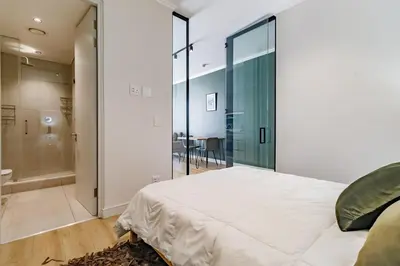 a bedroom with a large white bed and a glass wall at Ellipse Waterfall - Luxe Urban Escape in Midrand