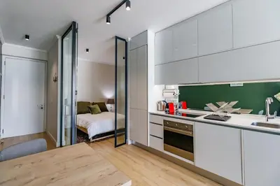 a kitchen with white cabinets and a bed in a room at Ellipse Waterfall - Luxe Urban Escape in Midrand