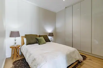 a white bedroom with a bed and a lamp at Ellipse Waterfall - Luxe Urban Escape in Midrand