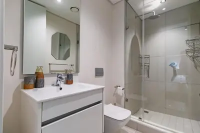 a white bathroom with a sink and a shower at Ellipse Waterfall - Luxe Urban Escape in Midrand