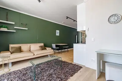 a living room with a couch and a clock on a wall at Ellipse Waterfall - Luxe Urban Escape in Midrand