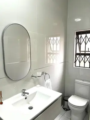 a white bathroom with a sink and a mirror at The Hill in Boschrand