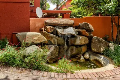 a fountain in a garden with rocks and flowers at City Retreat Safari Sunninghill in Sandton