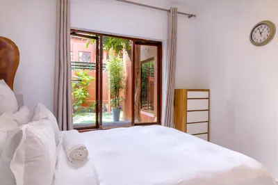 a bedroom with a white bed and a large window at City Retreat Safari Sunninghill in Sandton