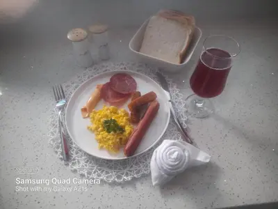a plate of breakfast food with sausage eggs and bacon at De Rams boutique guest house