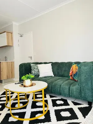 a woman laying on a green couch in a living room at The Legacy at The Blyde in Pretoria