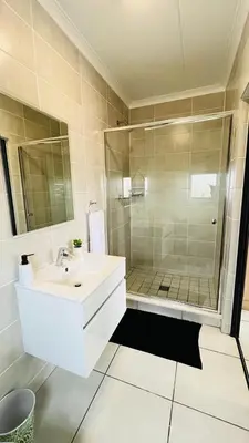 a white bathroom with a shower and a sink at The Legacy at The Blyde in Pretoria