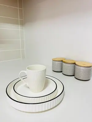 a white coffee cup on a plate next to a stack of plates at The Legacy at The Blyde in Pretoria