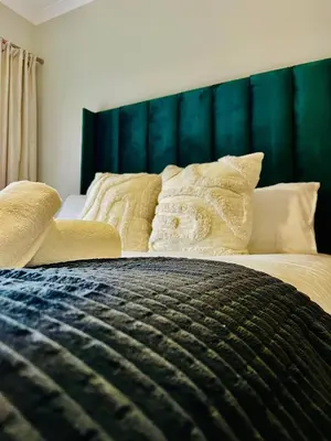 a bedroom with a large bed with a green headboard at The Legacy at The Blyde in Pretoria