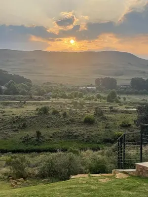 a view of a field with the sunset in the background at Walkerson Estate Country Home in Dullstroom