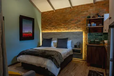 a bedroom with a bed and a brick wall at Gillford Alley luxury bachelor living in Benoni