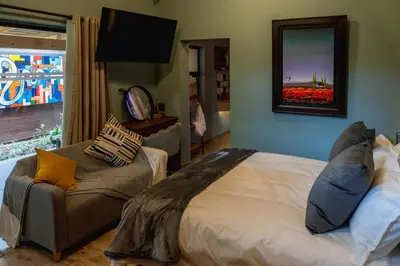a bedroom with a bed and a chair and a mirror at Gillford Alley luxury bachelor living in Benoni