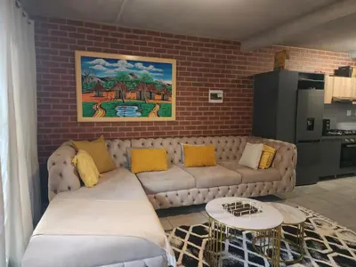 a living room with a couch and a brick wall at The pentagon luxury in Midrand