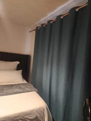 a bedroom with a bed and a blue curtain at The pentagon luxury in Midrand