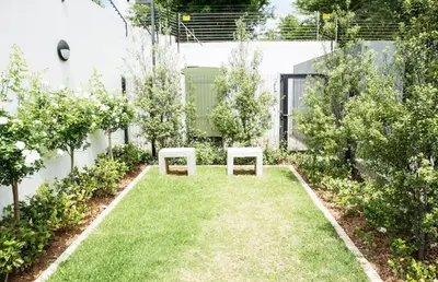 a garden with two benches in the grass at High End 93 On New Stay in Midrand