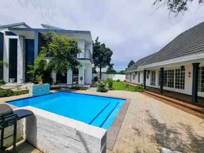 a swimming pool in front of a house at Bayley Boutique Guesthouse & Hydro Spa in Benoni