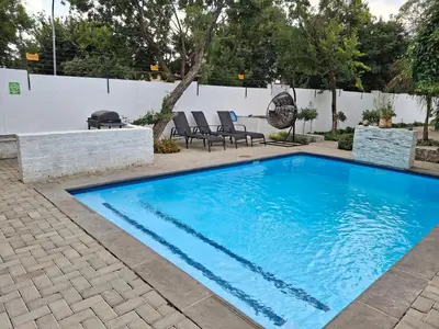 a swimming pool with blue water in a yard at Bayley Boutique Guesthouse & Hydro Spa in Benoni