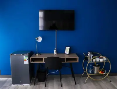 a desk with a television on a blue wall at Bayley Boutique Guesthouse & Hydro Spa in Benoni