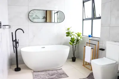 a bathroom with a large white tub and a toilet at Bayley Boutique Guesthouse & Hydro Spa in Benoni