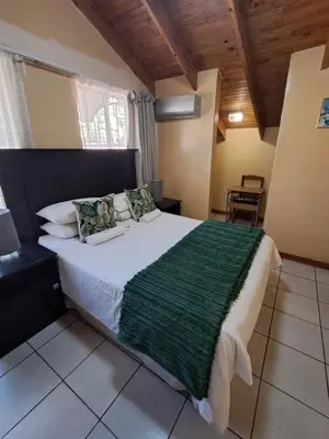a bedroom with a large bed with a green blanket at African Nights in Pretoria