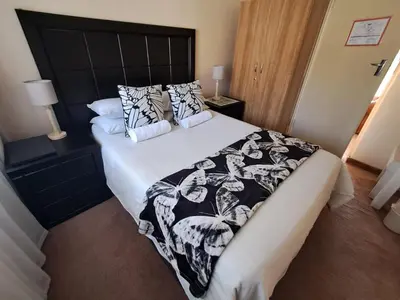 a bed with a black and white comforter and pillows at African Nights in Pretoria