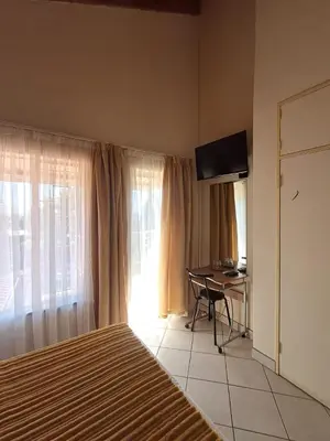 a bedroom with a bed and a desk and a television at African Nights in Pretoria
