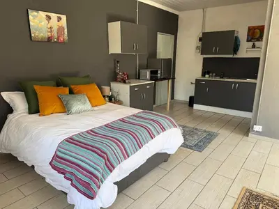 a bedroom with a large bed and a kitchen at Tierra de Sueños in Pretoria