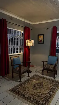 a living room with two chairs and red curtains at Tierra de Sueños in Pretoria