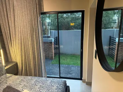 a bedroom with a view of a garden through a glass door at Waterkloof Park in Pretoria