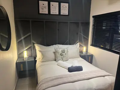 a bedroom with a large white bed with two lamps at Waterkloof Park in Pretoria