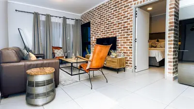 a living room with a couch and a brick wall at Mbombela Sunrise Retreat in Boschrand